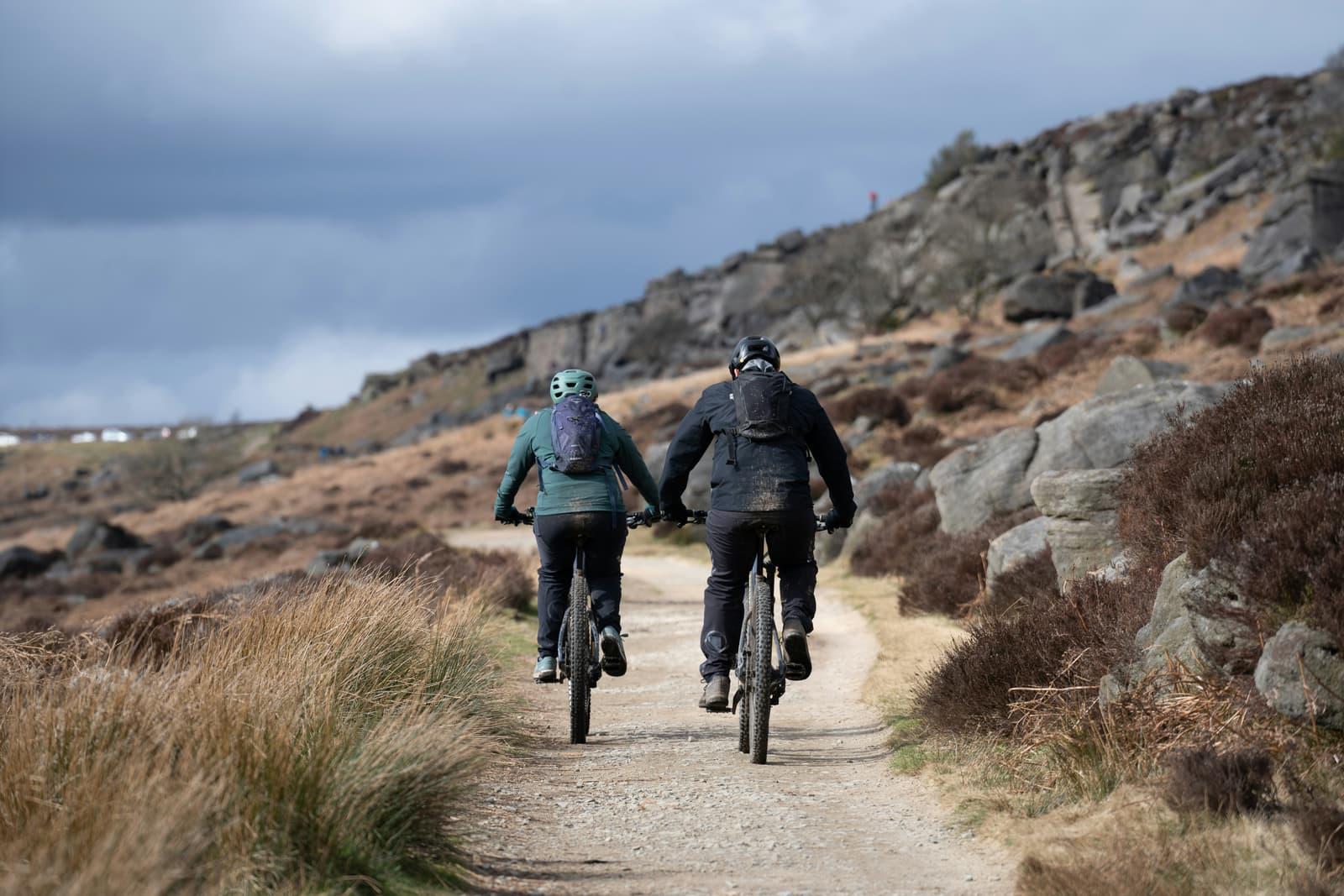 Active couple mountain biking a trail through the hills